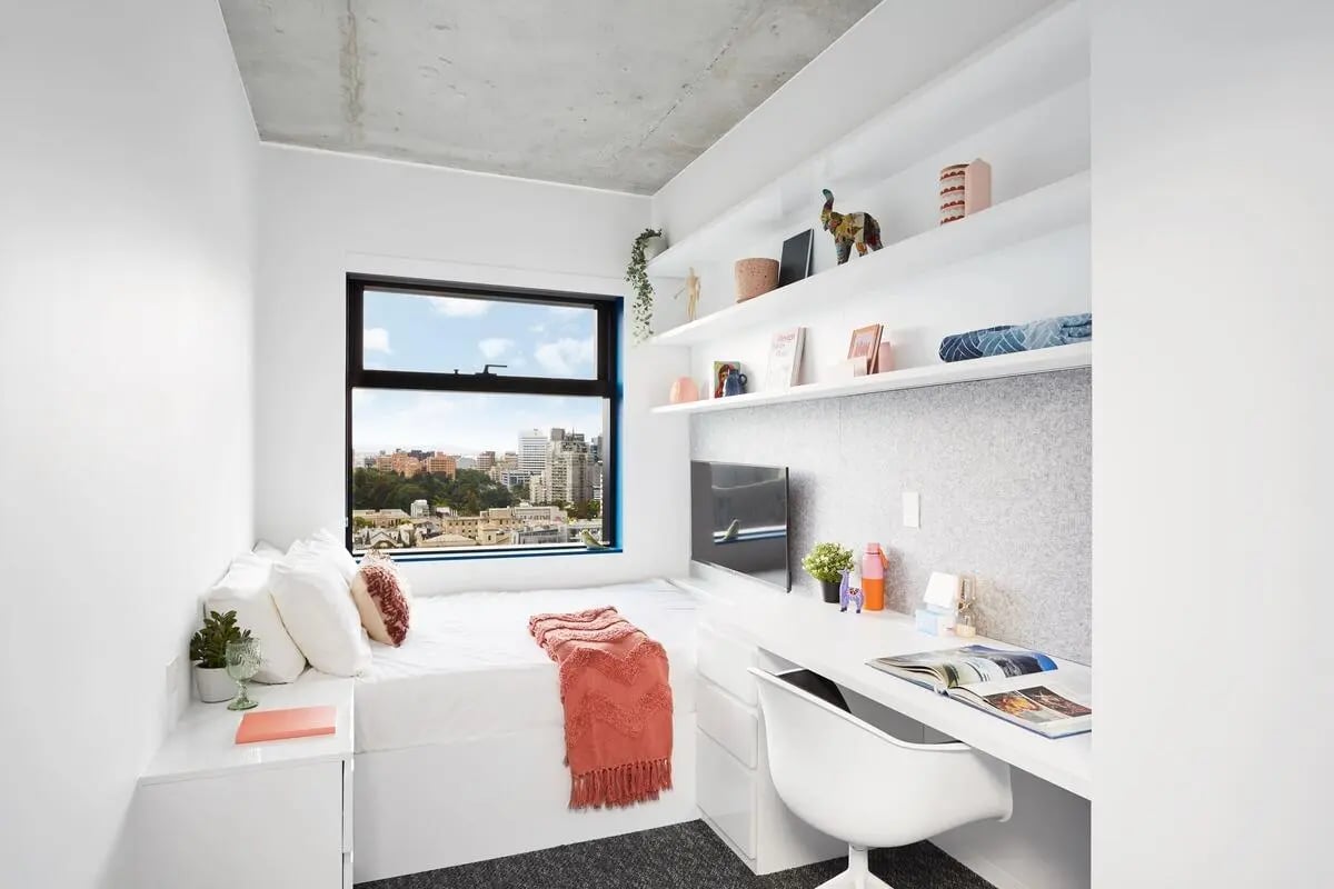 Bed desk and shelves with cityscape view bedroom at Scape Carlton in Melbourne Student Accommodation