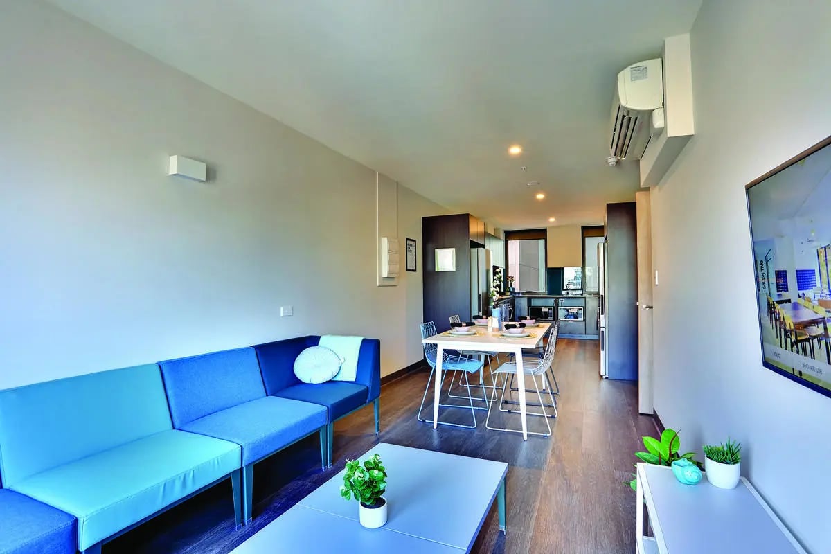 Blue sofa dining table and kitchen living room at Scape Adelaide University in Adelaide Student Accommodation