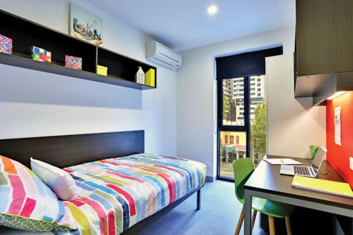 Bed with colorful bedding and desk workspace bedroom at Scape Melbourne Central in Melbourne Student Accommodation