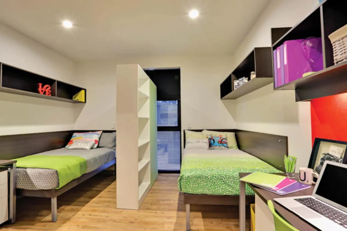 Two beds with colourful pillows and green blankets Bedroom at Scape Melbourne Central in Melbourne Student Accommodation