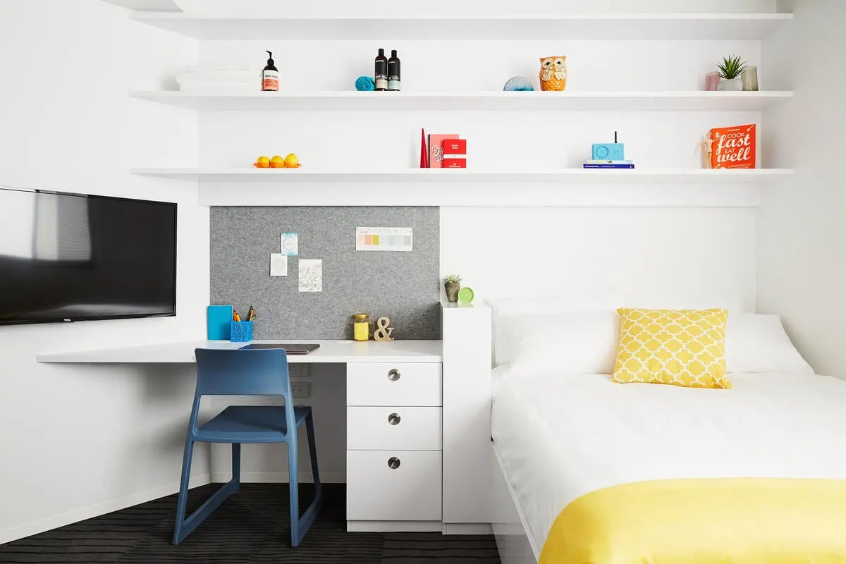 Desk chair television bed with yellow pillow Bedroom at Scape South Bank in Brisbane Student Accommodation