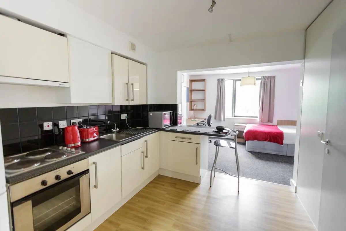 Kitchen with oven and bed visible Studio apartment at AXO Camden in London Student Accommodation