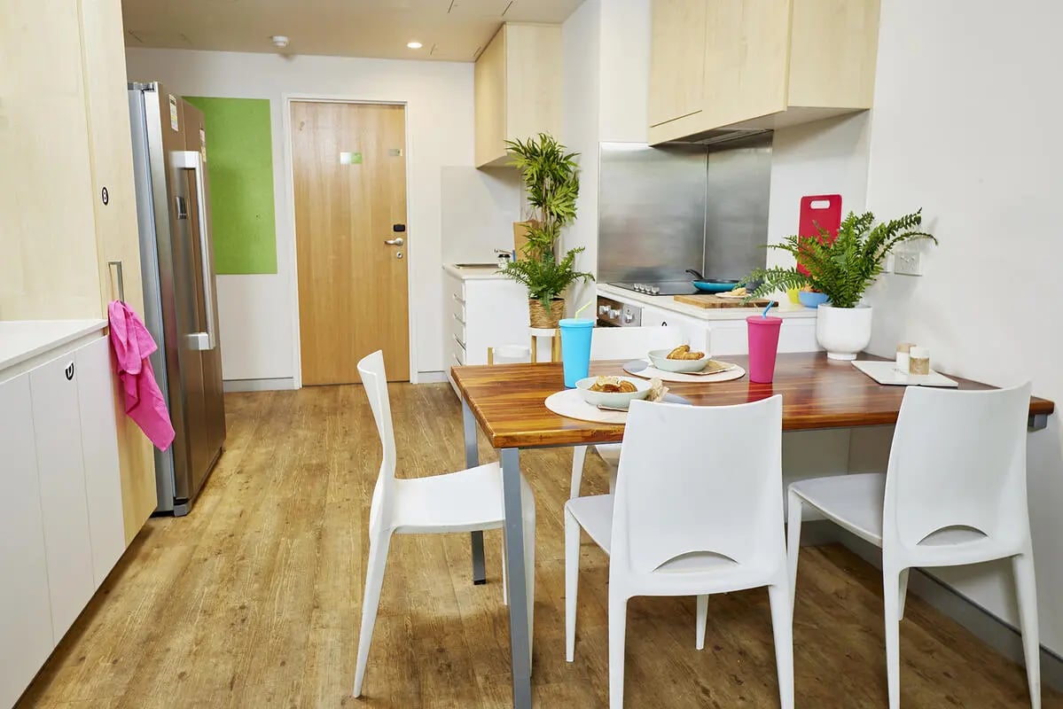 Dining table chairs refrigerator and kitchen area kitchen at Scape Cleveland in Sydney Student Accommodation