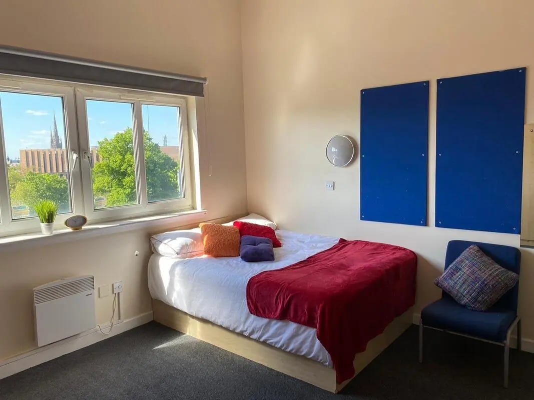Bed with red blanket pillows blue chair bedroom at AXO Paradise Student Village in Coventry Student Accommodation