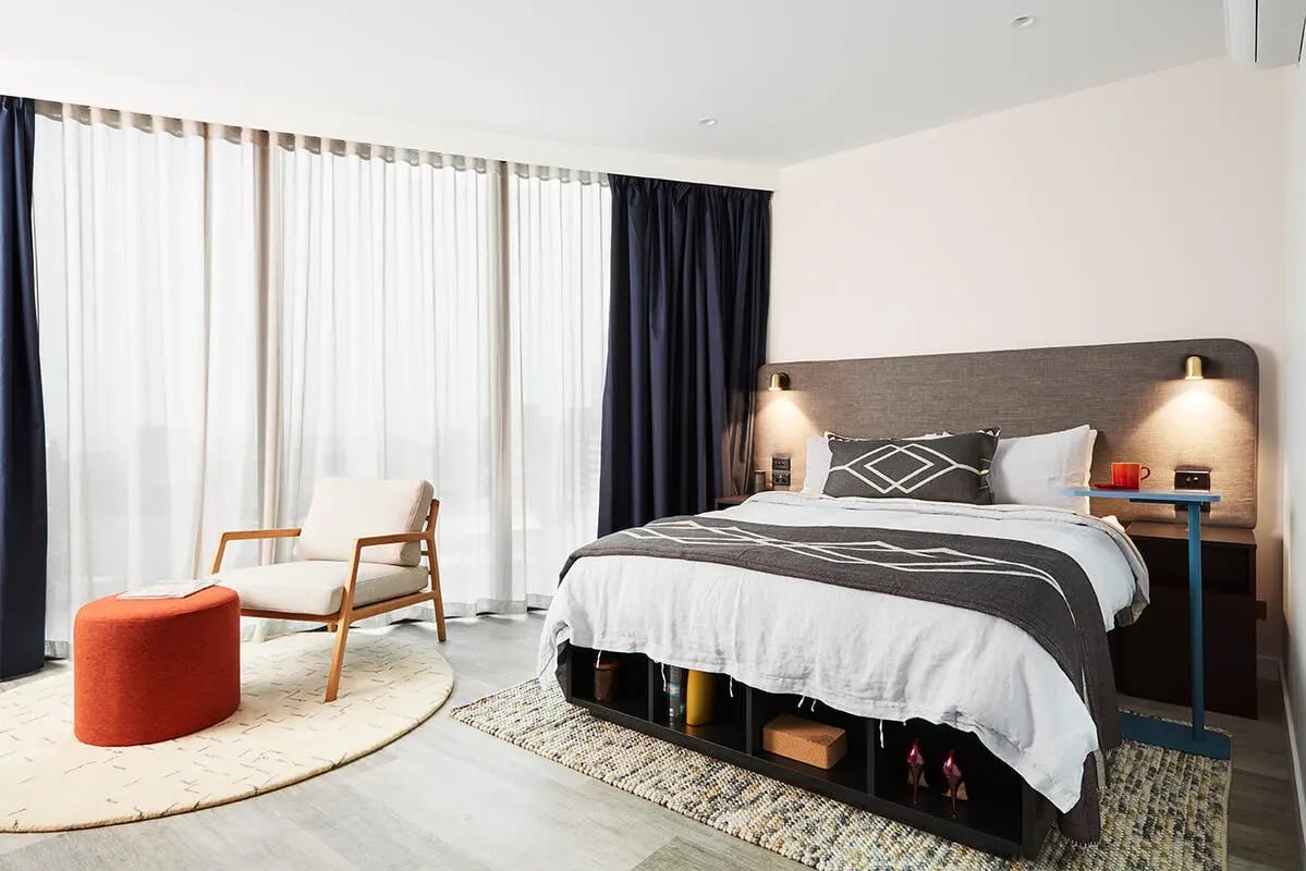 Bed chair ottoman under large windows bedroom at Scape Aurora in Melbourne Student Accommodation