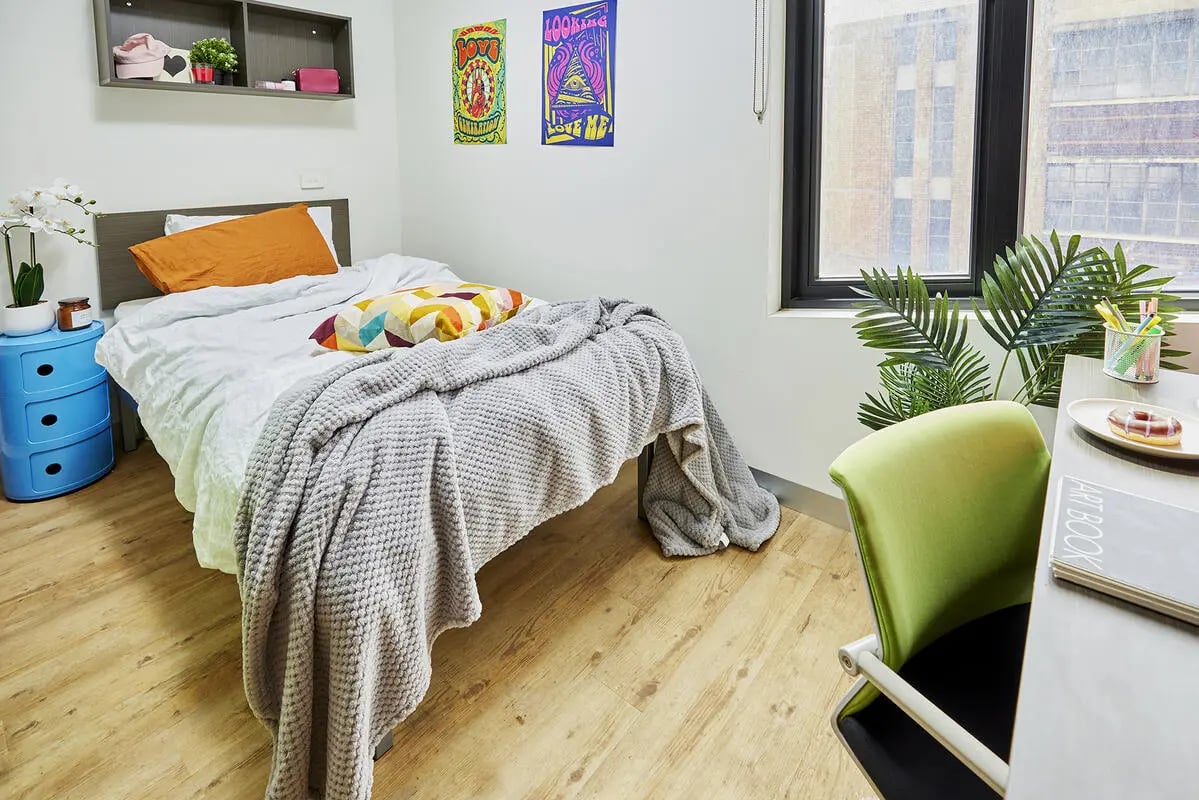 Bed desk chair plants and posters bedroom at Scape Berkeley in Melbourne Student Accommodation