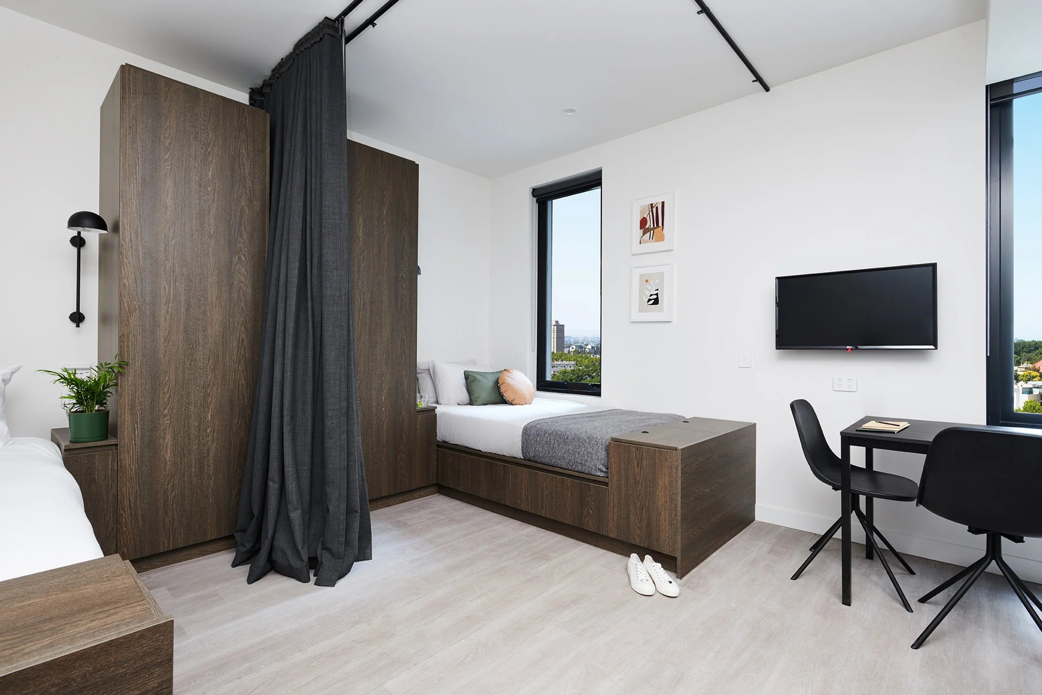 Bed desk TV with dark cabinets and curtain Bedroom at Scape Cornell Place in Melbourne Student Accommodation