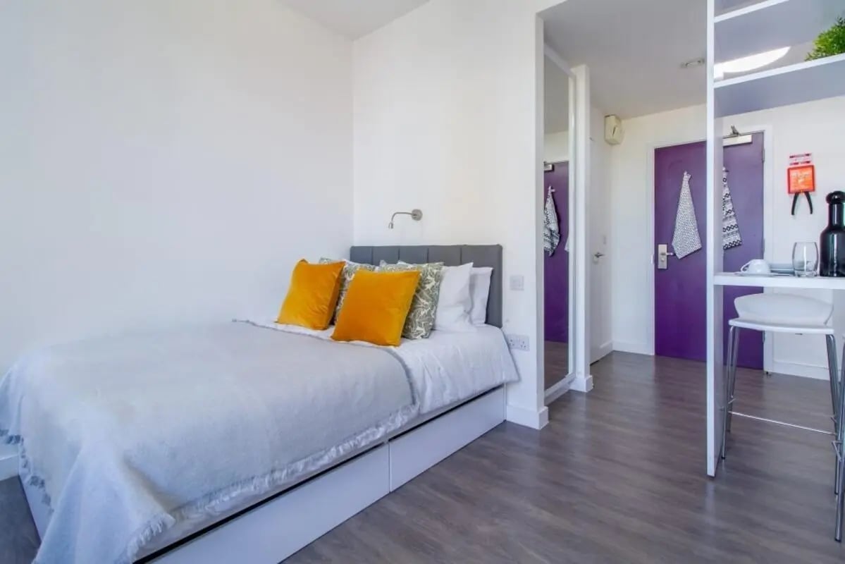 Bed with orange pillows and a desk study area Bedroom at Kensington House in Birmingham Student Accommodation