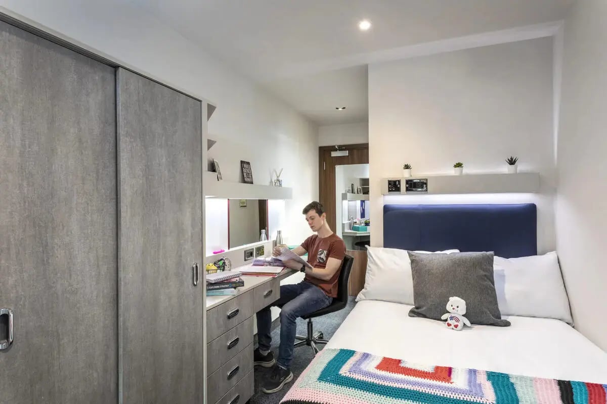 Student studying at desk next to bed Bedroom at Brotherton House in Leeds Student Accommodation