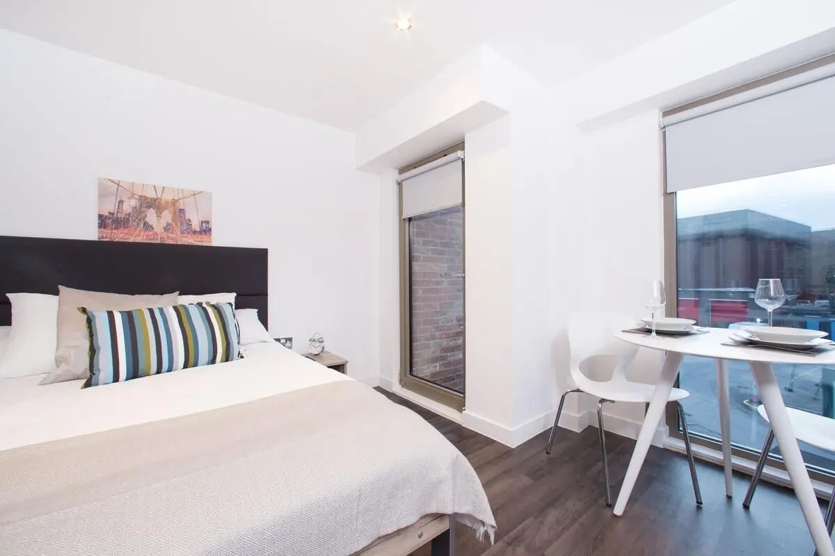 Bed with decorative pillows and dining table bedroom at Northgate Point in Chester Student Accommodation