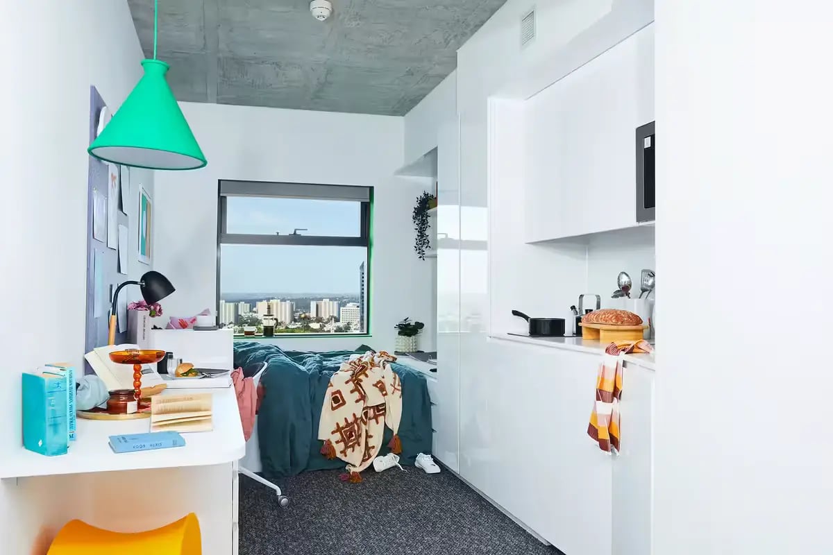 Desk bed kitchen area and city view studio at Scape Franklin in Melbourne Student Accommodation
