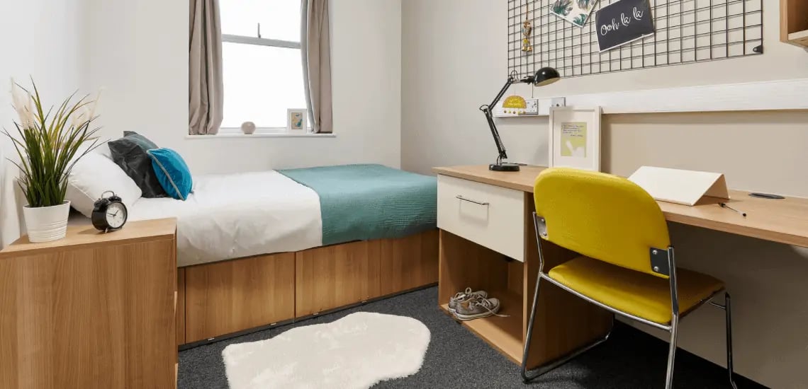 Bed desk plant alarm clock yellow chair bedroom at Northernhay House in Exeter Student Accommodation