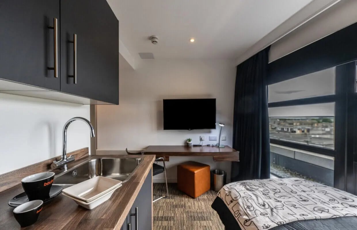 Sink desk TV bed with patterned blanket bedroom at Bauhaus Student Langstane Place in Aberdeen Student Accommodation