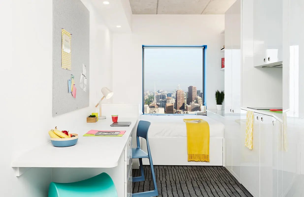 Desk chair bed with yellow throw bedroom at Scape Swanston in Melbourne Student Accommodation