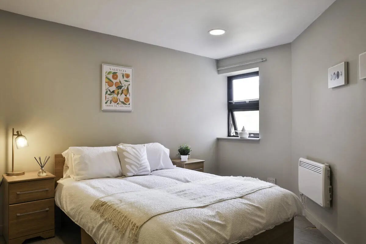 Bed with white bedding nightstand lamp painting Bedroom at Ladybarn House in Manchester Student Accommodation