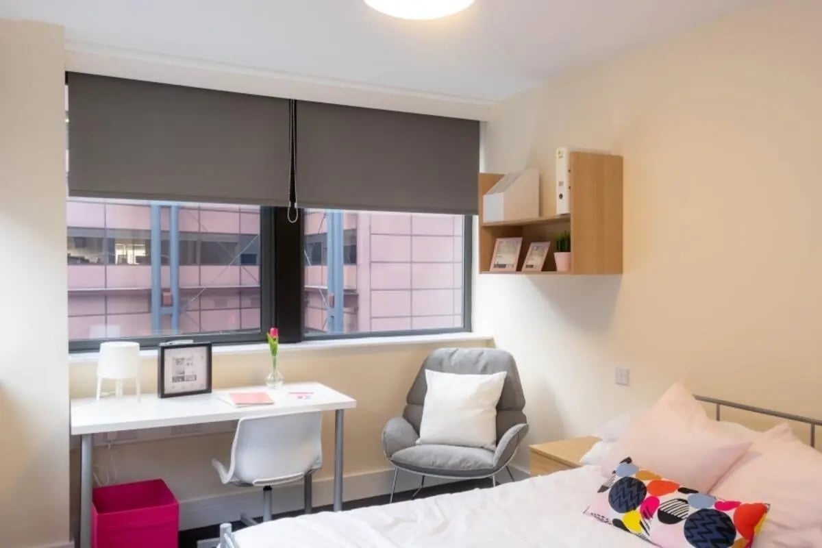 Desk chair bed bookshelf and pink bin bedroom at Newton House Glasgow in Glasgow Student Accommodation