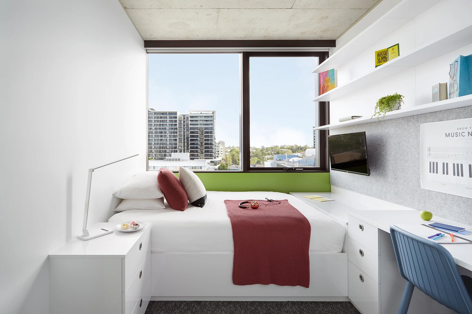 Bed with red throw headphones and desk bedroom at Scape Toowong in Brisbane Student Accommodation
