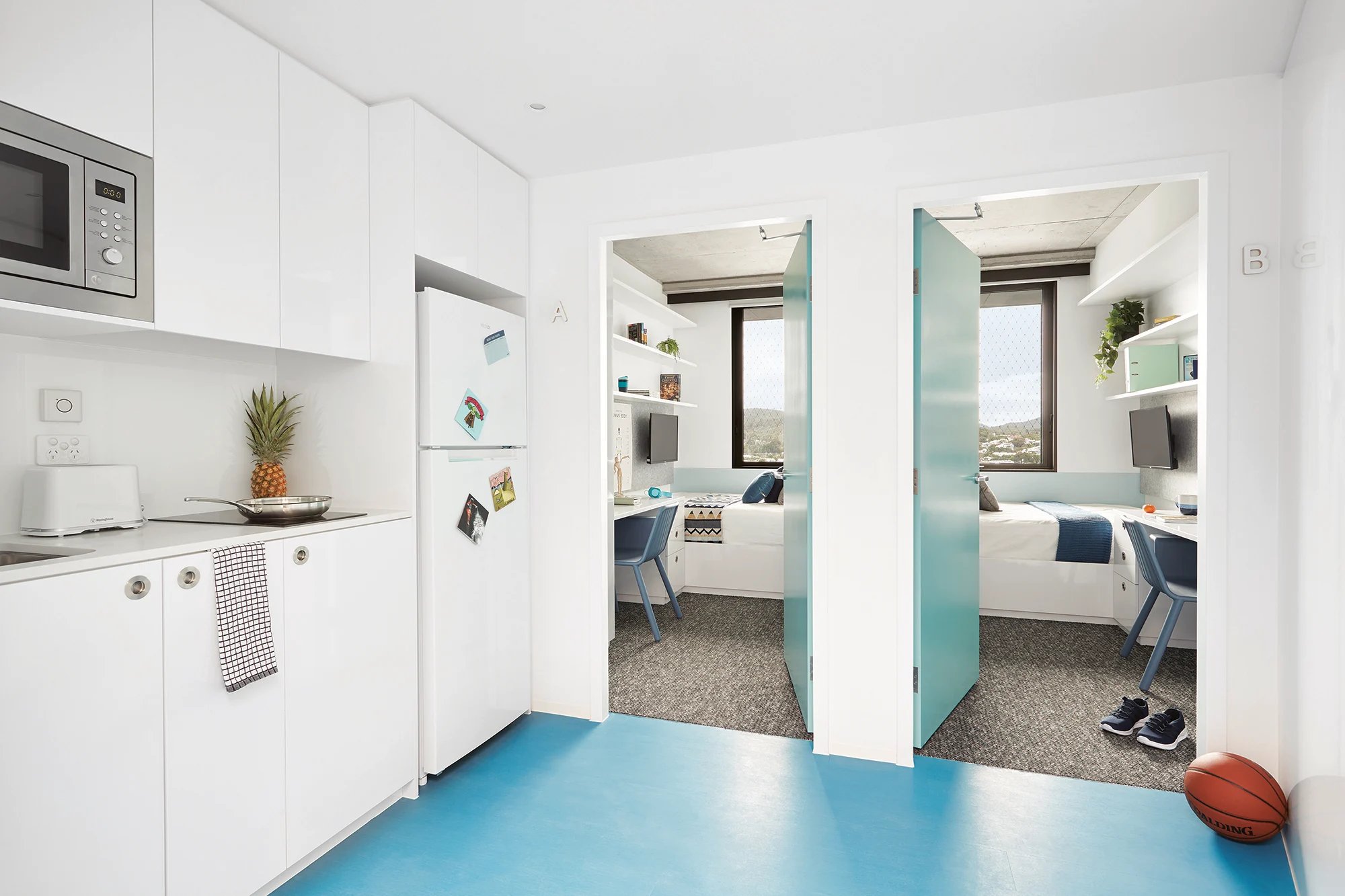 Kitchen with fridge and two bedrooms beyond at Scape Toowong in Brisbane Student Accommodation