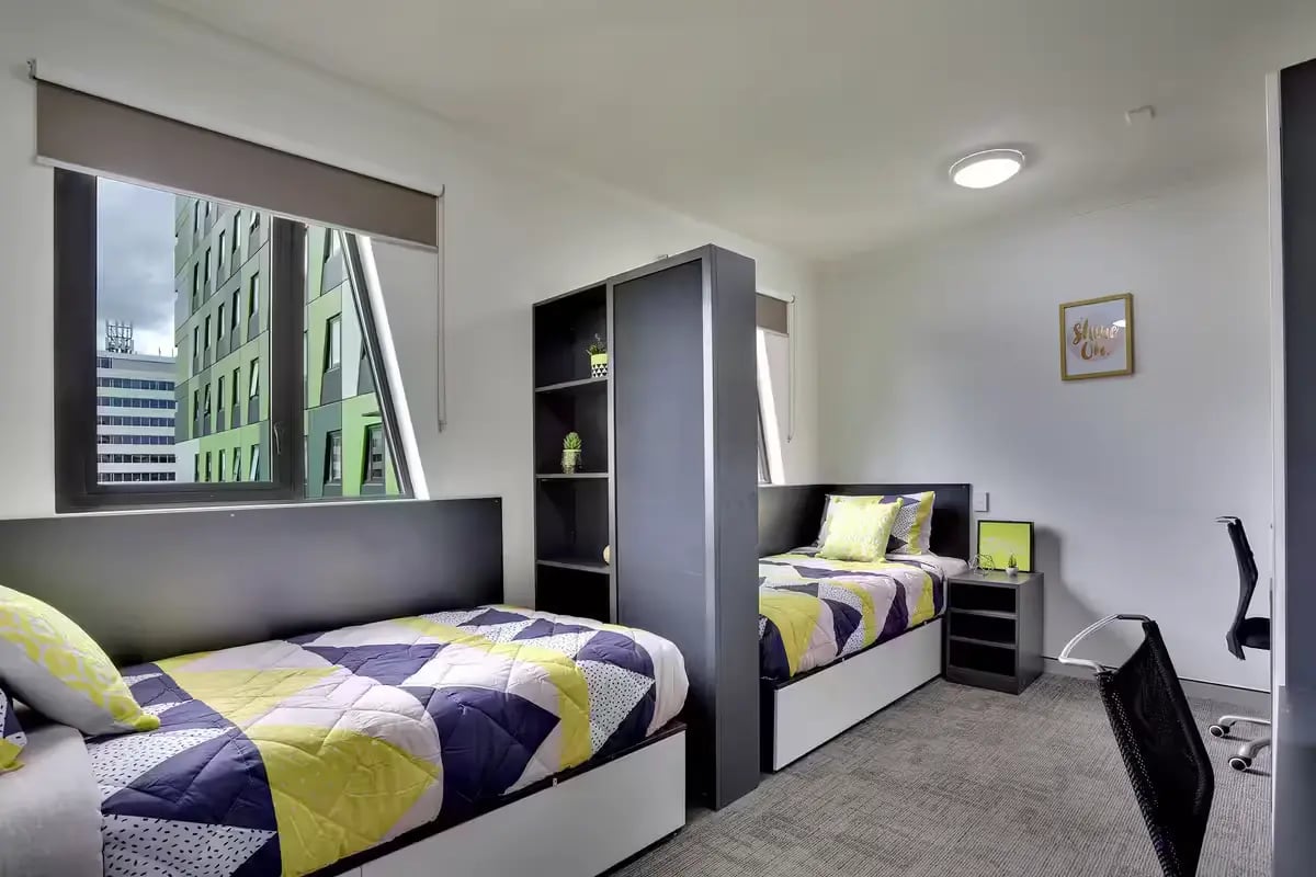 Two beds shelf desk and chairs bedroom at Scape Tribune in Brisbane Student Accommodation