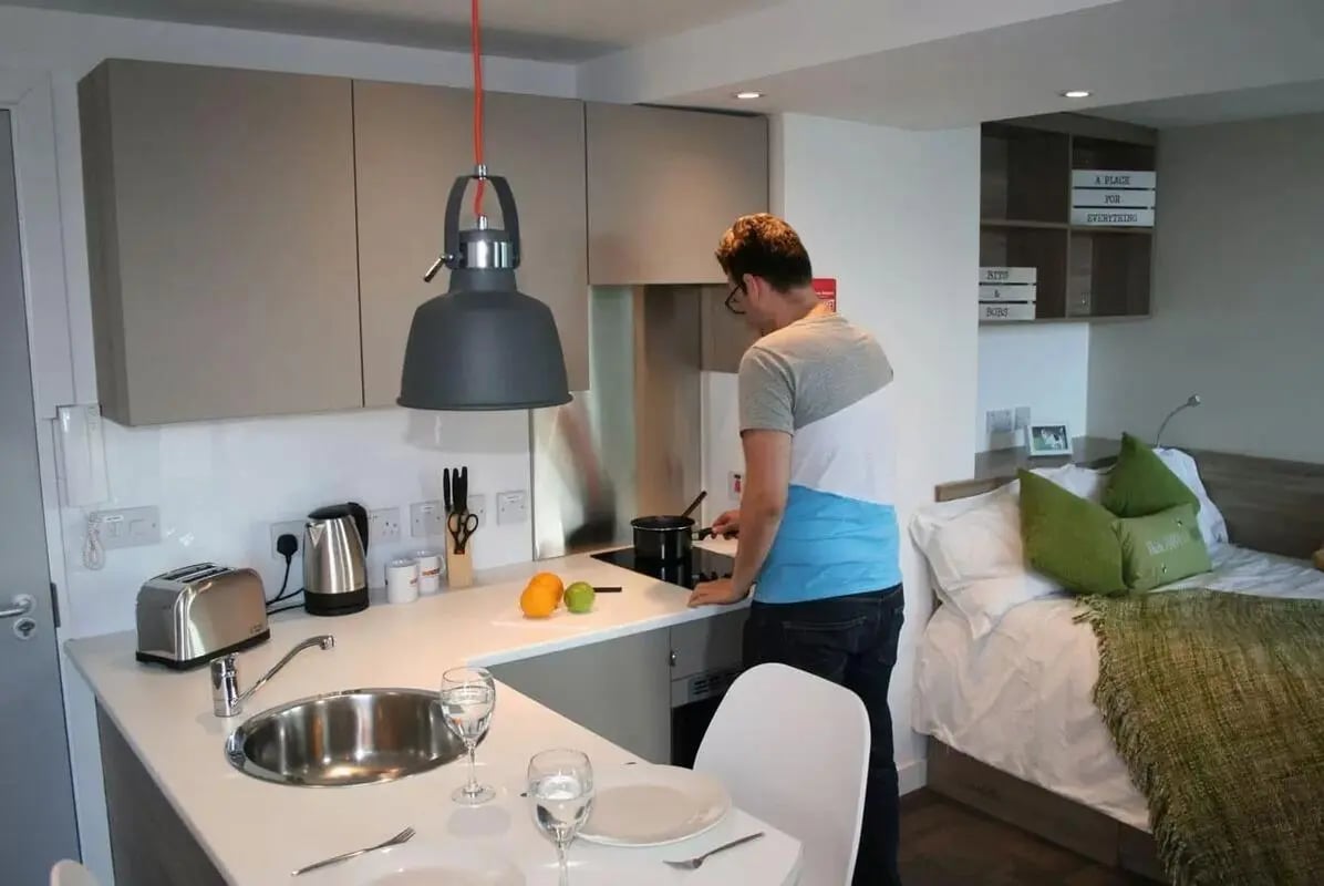 Kitchen and bedroom with man cooking studio apartment at CityBlock Penny Street in Lancaster Student Accommodation