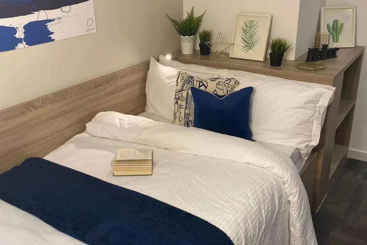 Bed with blue and patterned pillows and book bedroom at CityBlock Penny Street in Lancaster Student Accommodation
