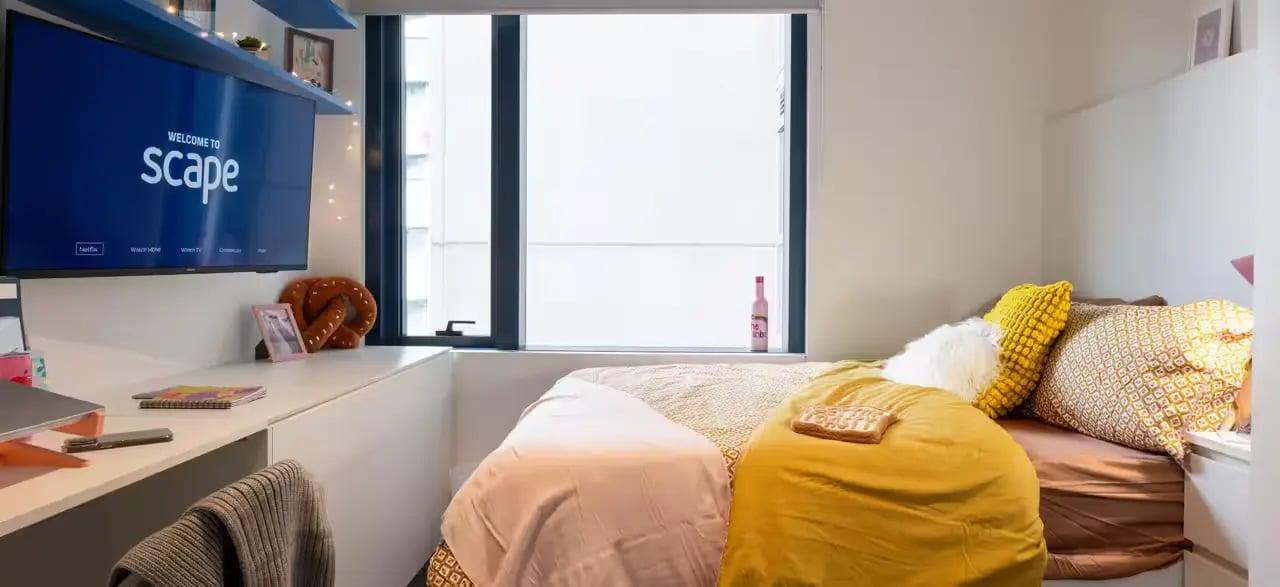 Bed with yellow pillows and desk area Bedroom at Scape Leicester in Melbourne Student Accommodation