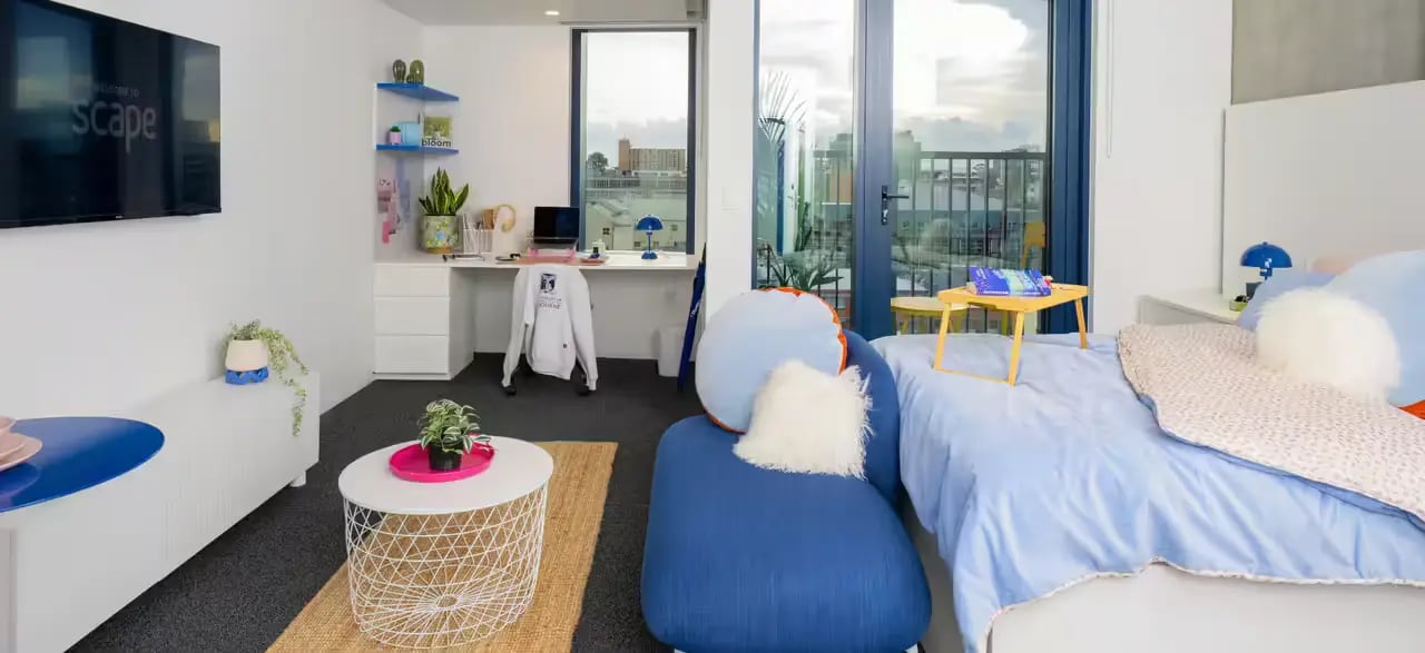 Bed desk chair blue pillows living room bedroom at Scape Leicester in Melbourne Student Accommodation