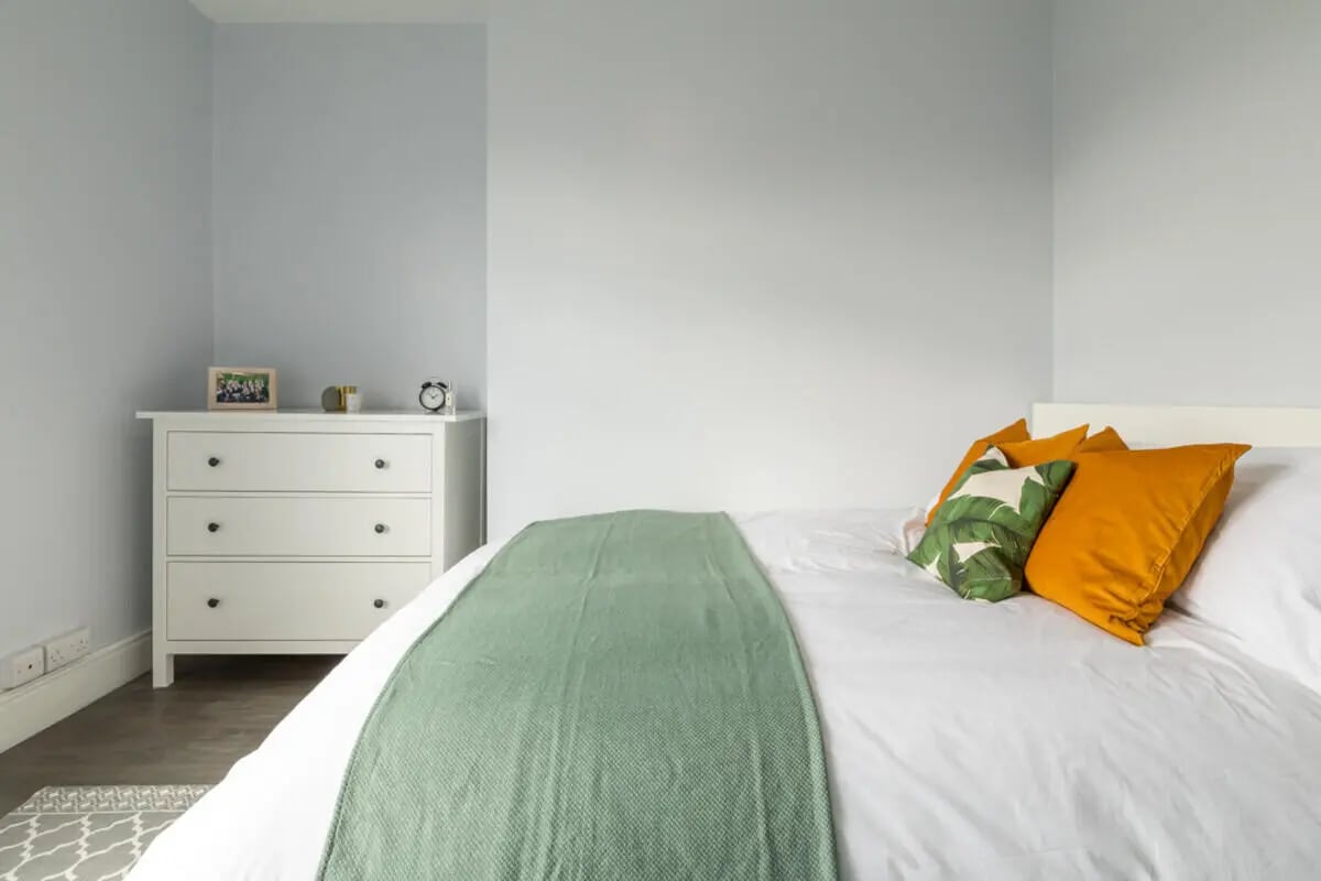 White dresser bed with green throw and pillows bedroom at Holgate Road in York Student Accommodation