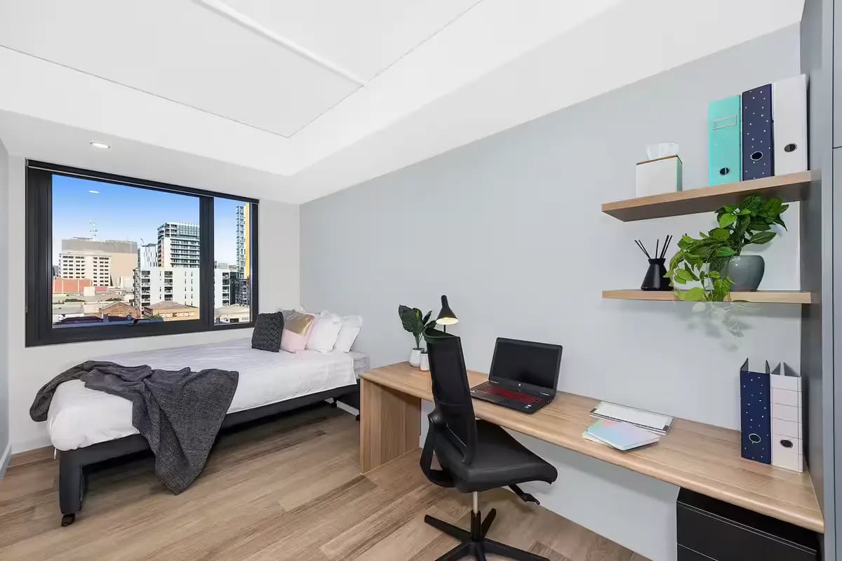 Bed desk chair laptop shelves binders plant Bedroom at Scape Waymouth in Adelaide Student Accommodation
