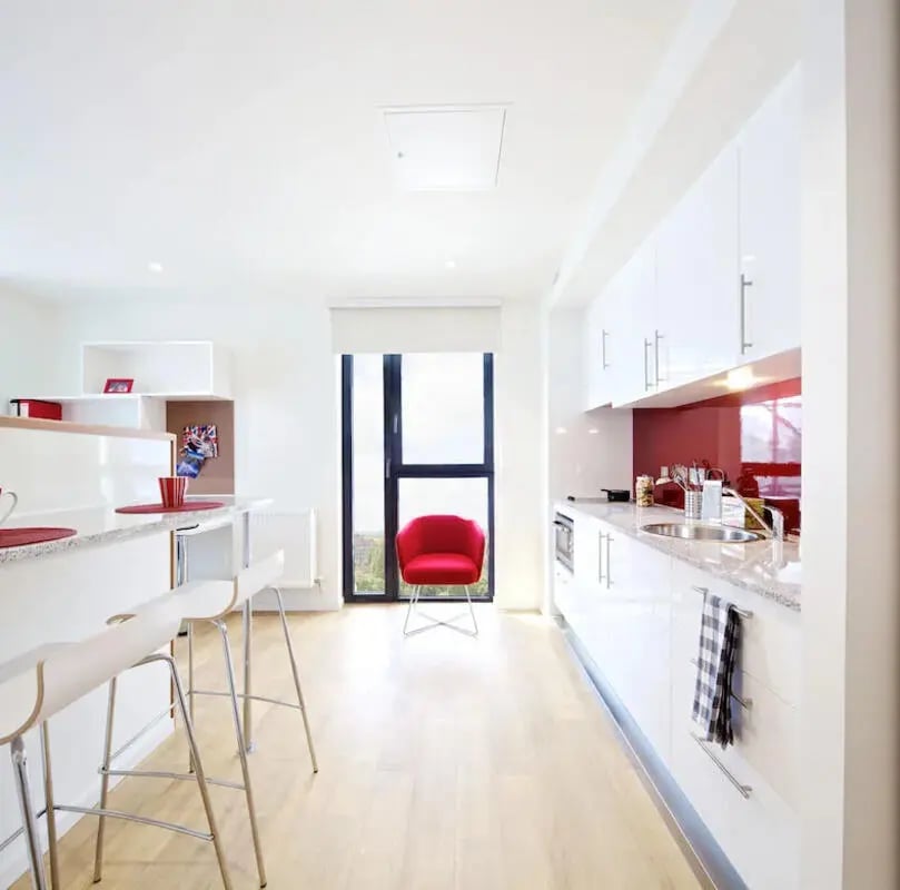 Modern kitchen with white cabinets red chair kitchen area at Wood Lane Studios in London Student Accommodation