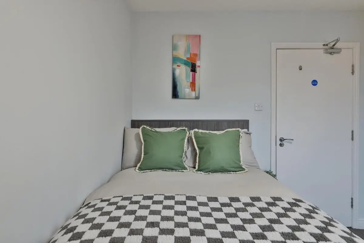 Bed with green pillows and checkered blanket bedroom at Royal Park Road in Leeds Student Accommodation