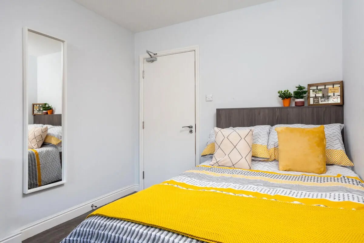 Bed with yellow blanket and pillows bedroom at Royal Park Road in Leeds Student Accommodation