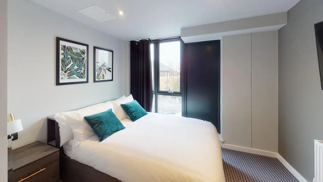 Bed with teal pillows and artwork bedroom at Astra House in London Student Accommodation
