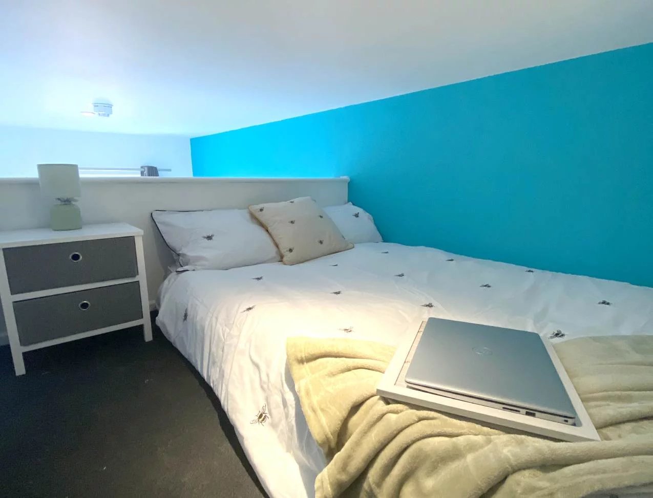 Bed with bee duvet bedside table and laptop Bedroom at Radmoor House in Loughborough Student Accommodation