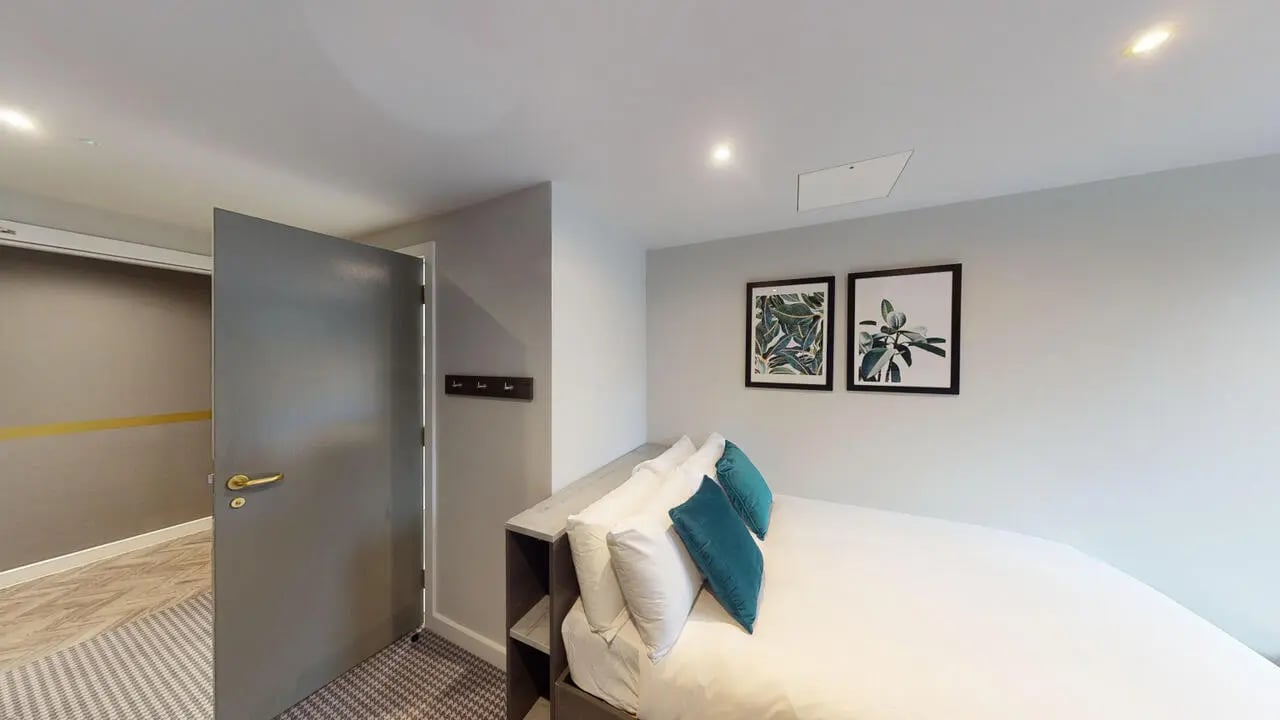 Bed with pillows door art and coat rack bedroom at Astra House in London Student Accommodation