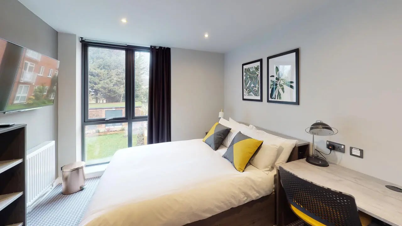Bed with yellow pillows desk and lamp bedroom at Astra House in London Student Accommodation