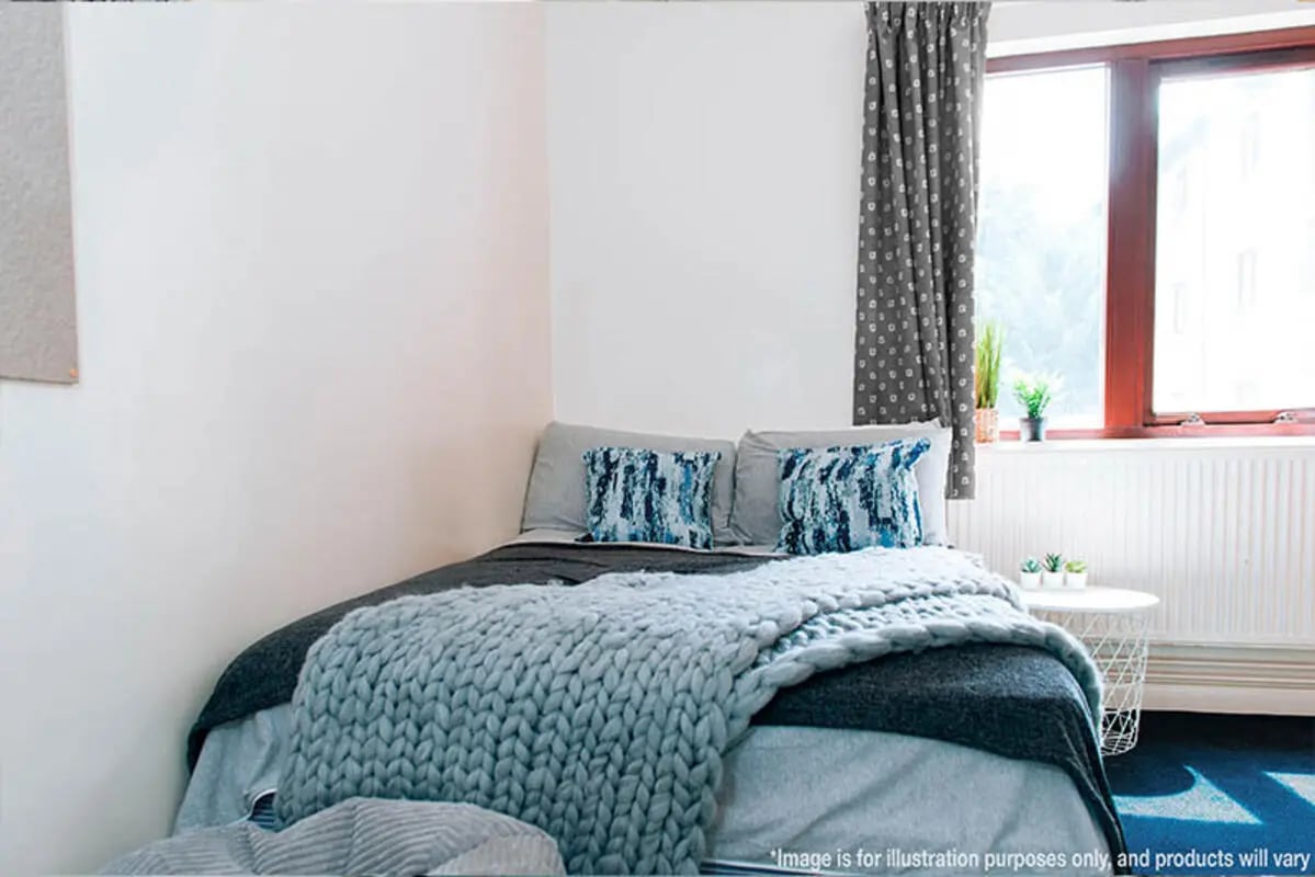 Bed with blue pillows and grey throws bedroom at Oxley Residence in Leeds Student Accommodation