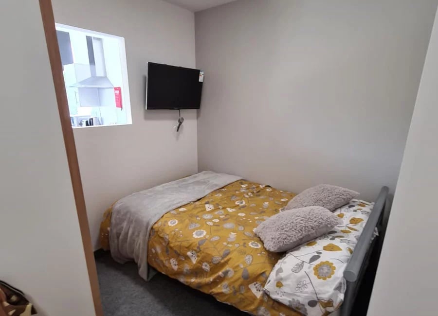 Bed with yellow floral duvet grey blanket two pillows bedroom at Salisbury Road in Leicester Student Accommodation