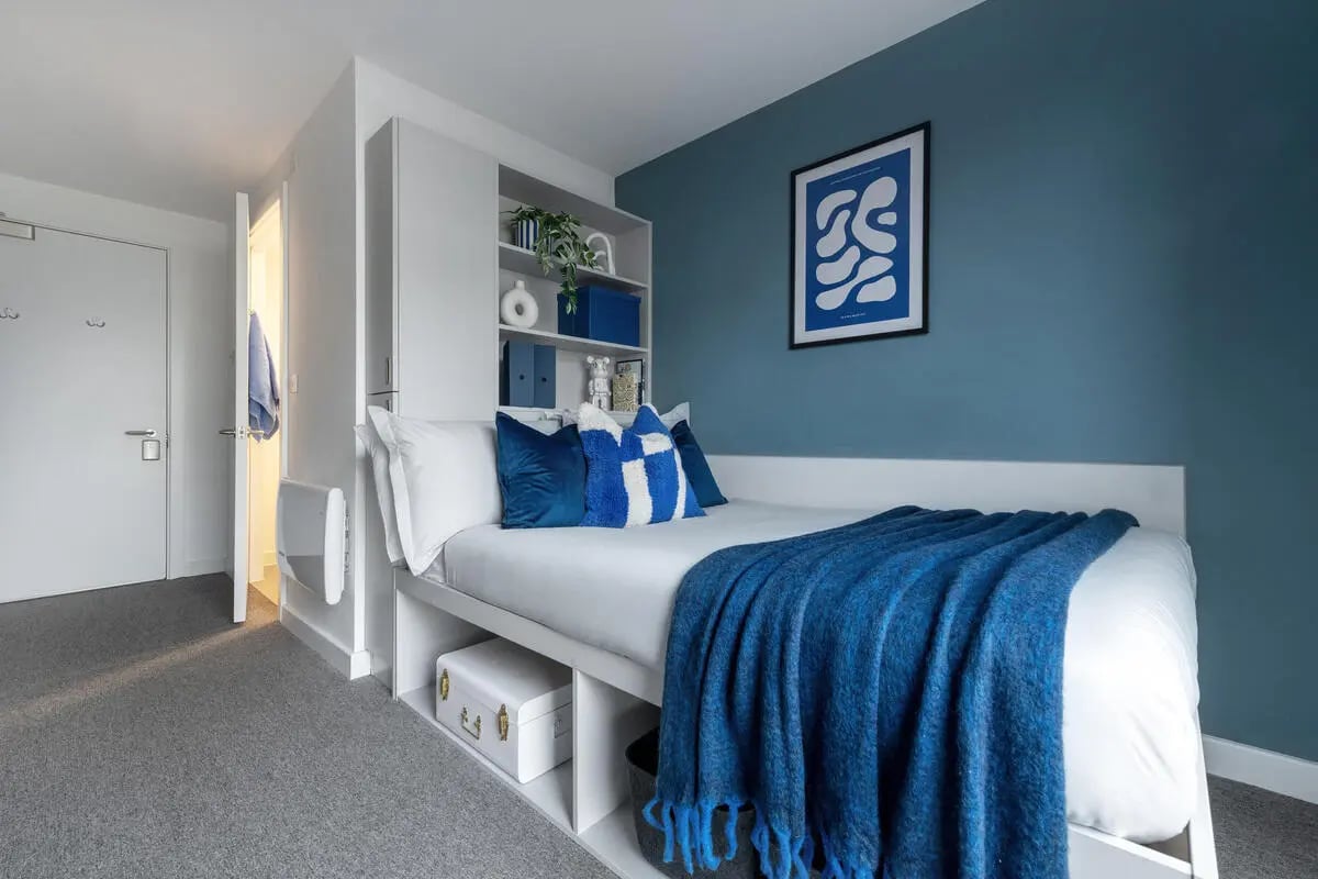 Bed with blue throw built-in shelves artwork Bedroom at Infinity Coventry in Coventry Student Accommodation