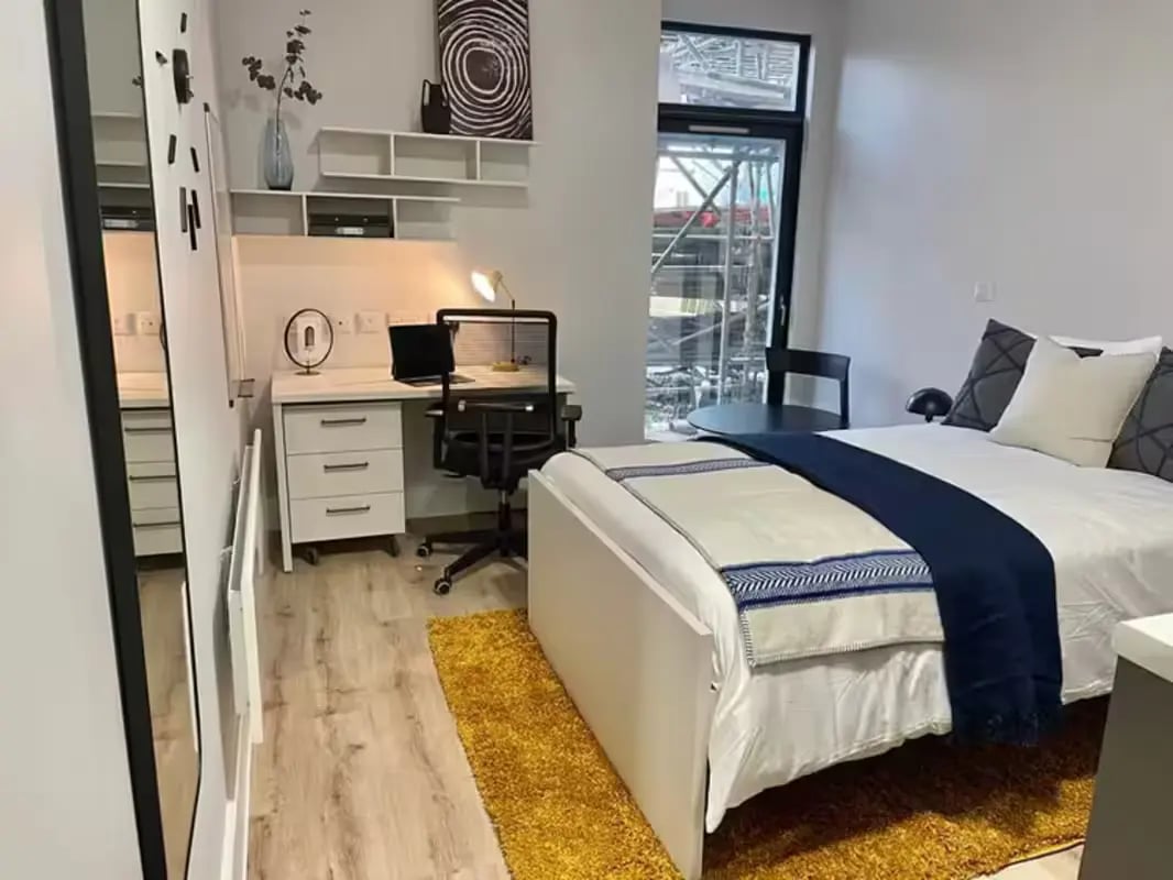 Bed desk chair and yellow rug bedroom at Hydrogen Falmouth in Falmouth Student Accommodation