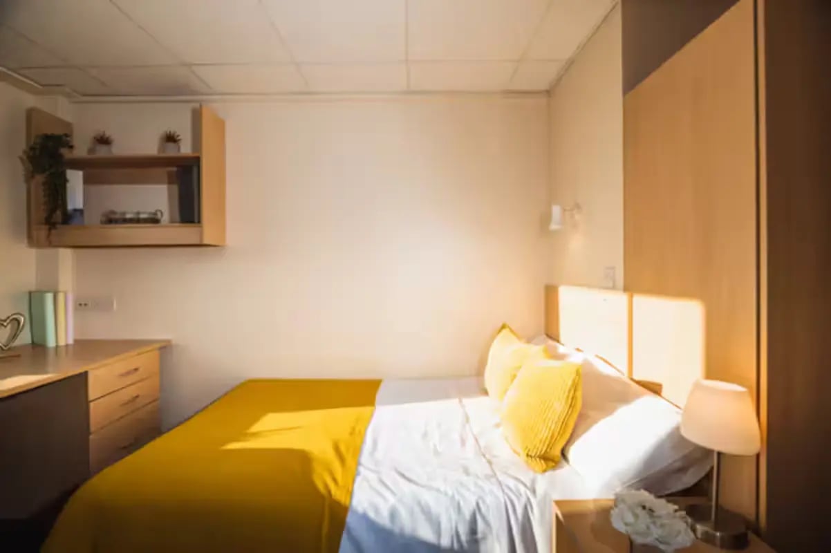 Bed with yellow covers and pillows student bedroom at The Junxion Lincoln in Lincoln Student Accommodation