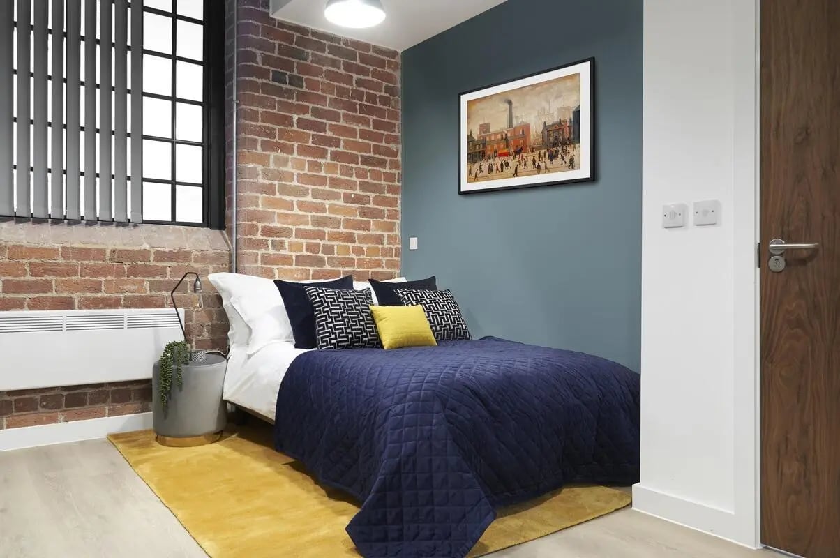 Bed with blue quilt art picture brick bedroom at Silk Mill Lancaster in Lancaster Student Accommodation