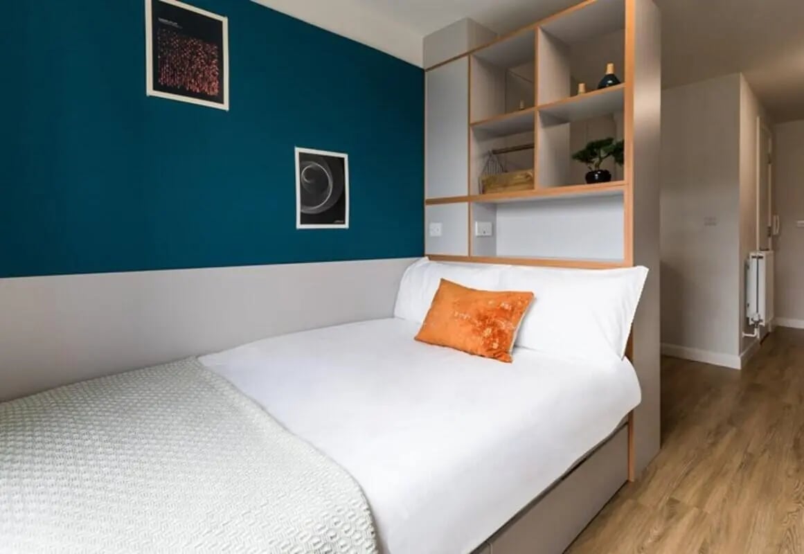 Bed with orange pillow and shelving unit bedroom at Stoneworks in Brighton Student Accommodation