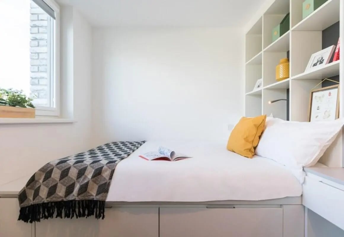 Bed with yellow pillow and patterned blanket bedroom at Vogue Studios in Brighton Student Accommodation