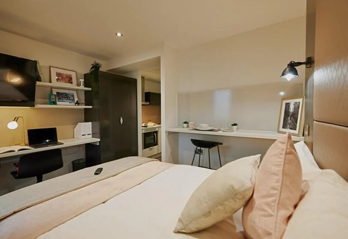 Desk TV wardrobe and kitchen living area at aparto Glasgow West End in Glasgow Student Accommodation