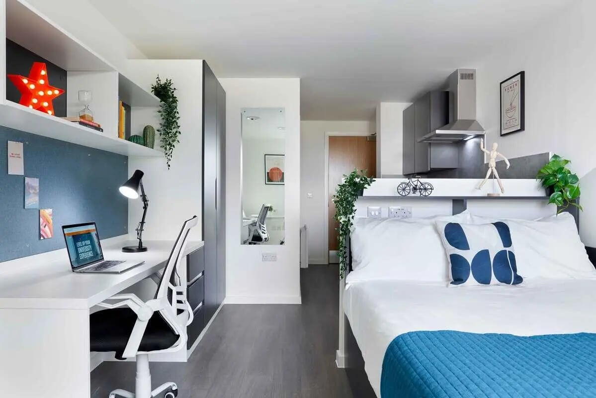 Desk lamp laptop bed with blue pillows and plants bedroom at Edinburgh Westfield in Edinburgh Student Accommodation