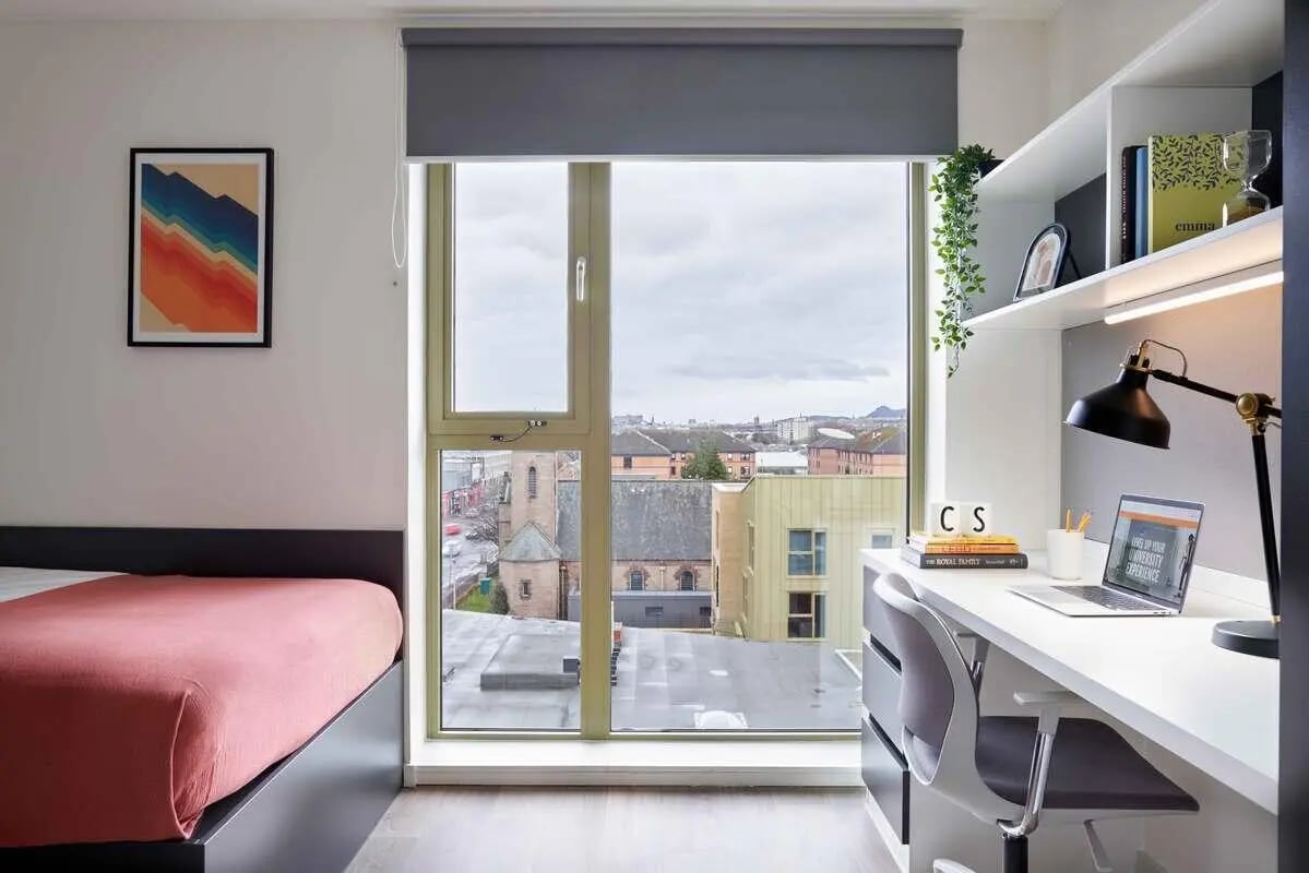 Bed desk lamp laptop bookshelves artwork bedroom study area at Edinburgh Gorgie in Edinburgh Student Accommodation