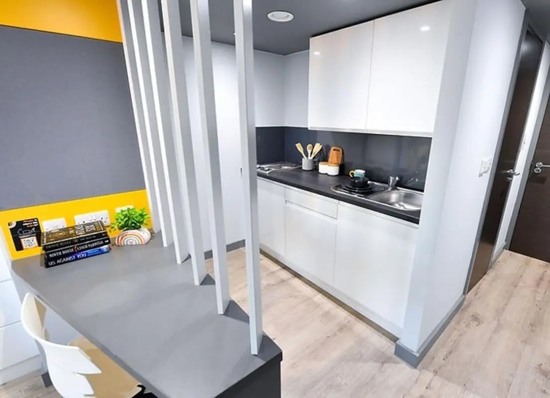 Desk books plant and kitchen area exterior at The Bank Leicester in Leicester Student Accommodation