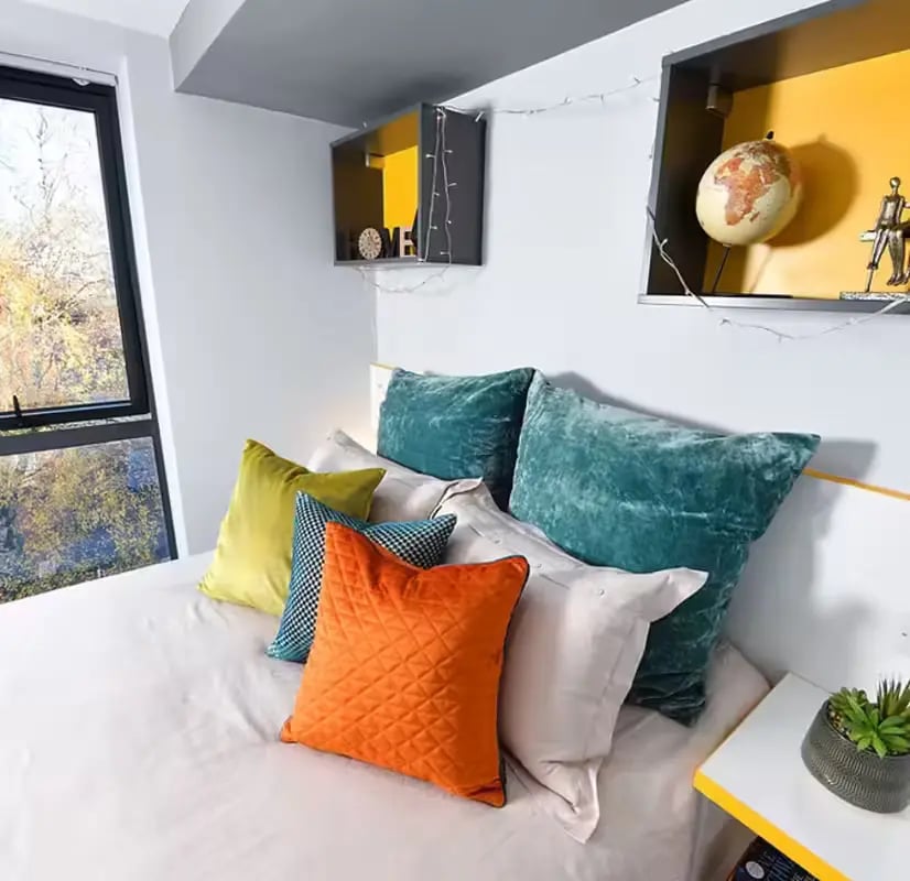 Bed with colorful pillows and modern shelves bedroom at The Bank Leicester in Leicester Student Accommodation
