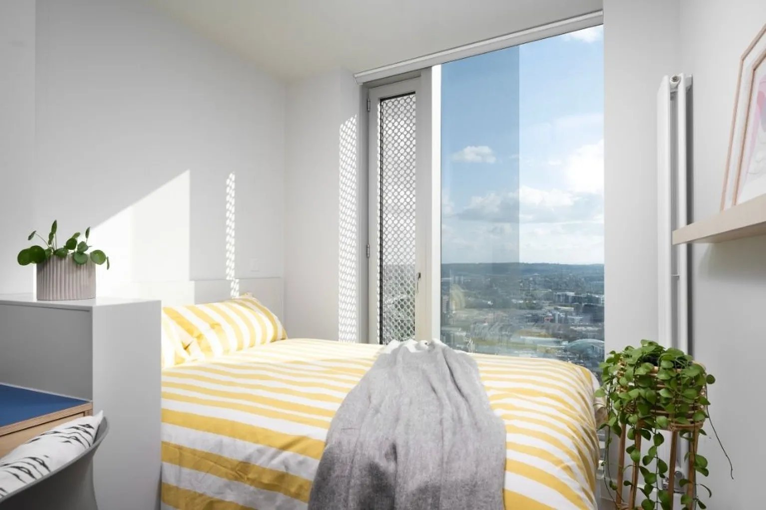 Bed with yellow striped duvet gray blanket bedroom at Scape Leeds in Leeds Student Accommodation